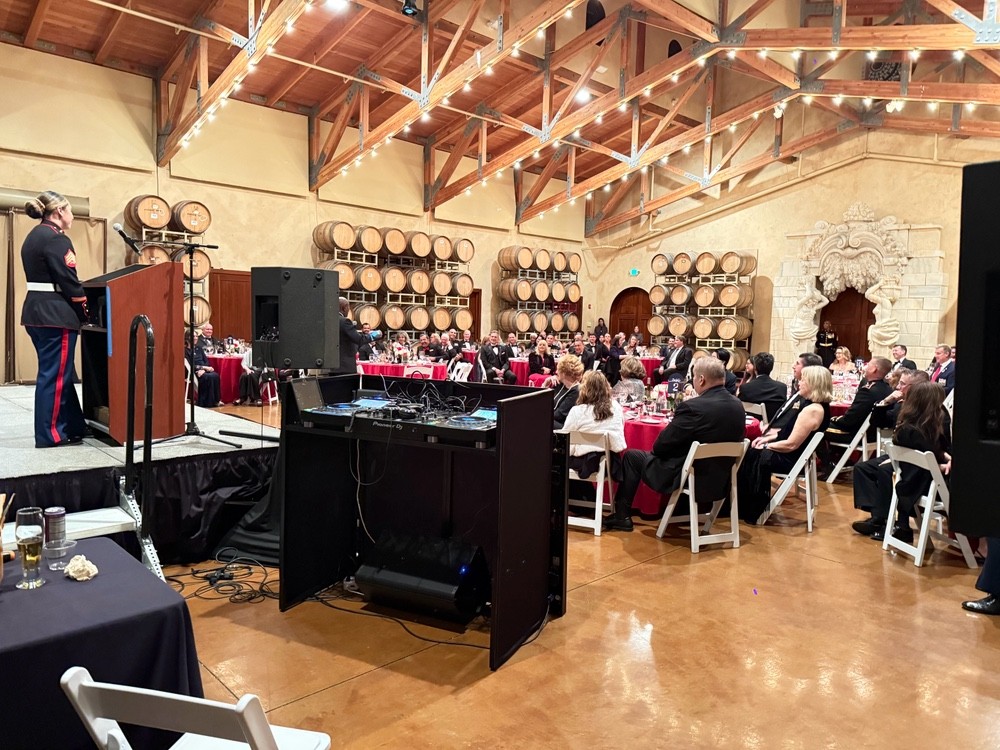 Guests seated for a formal program with DJ sound equipment in a winery-style event room